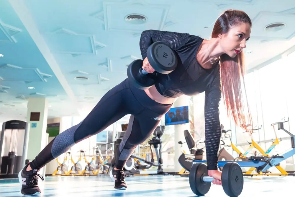 Woman with long brown hair exercising in a gym.