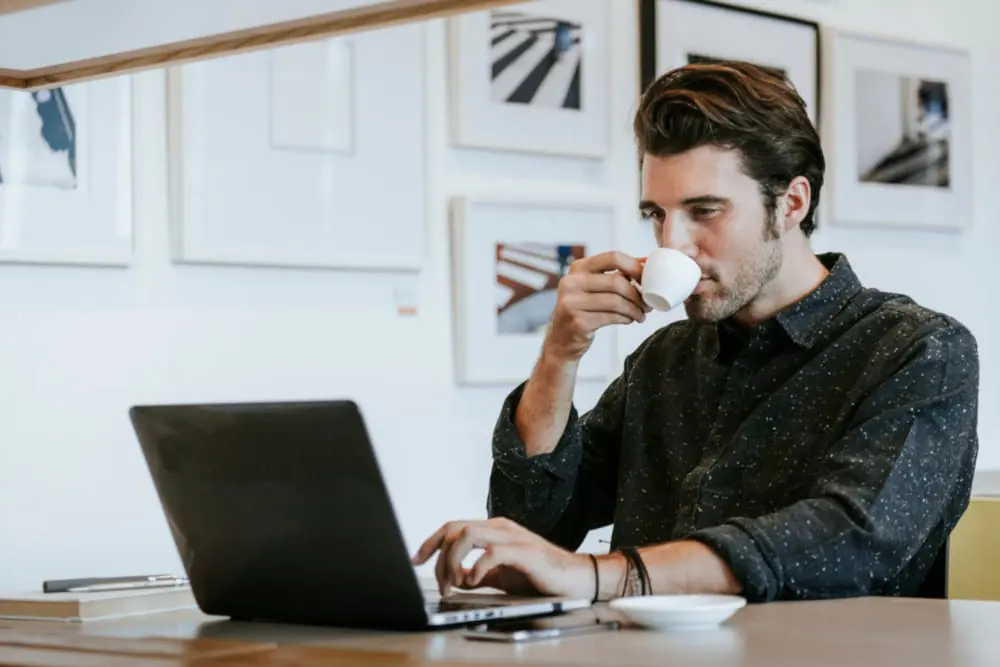 Man sipping a coffee while working