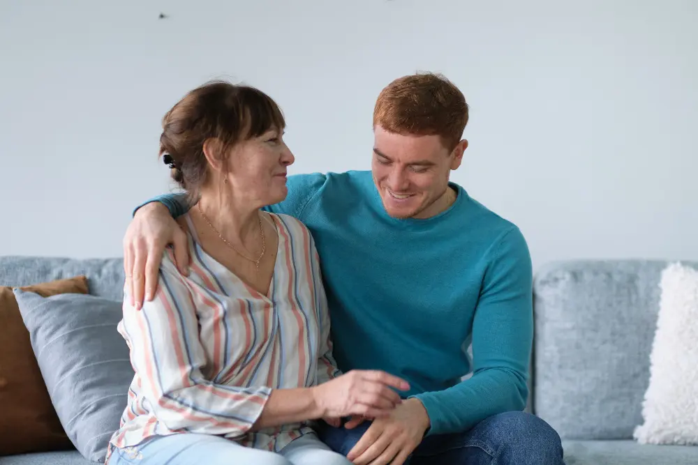 Cheerful elderly woman sitting on the sofa next to his adult son. adult son and mom talk to each other