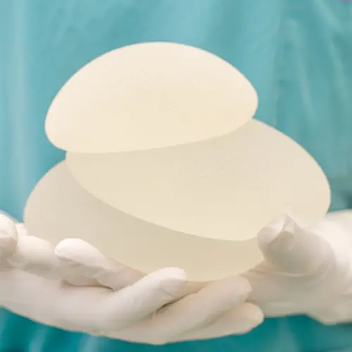 Silicone breast impalnts Two silicone breast implants held by gloved hands in a sterile medical setting.