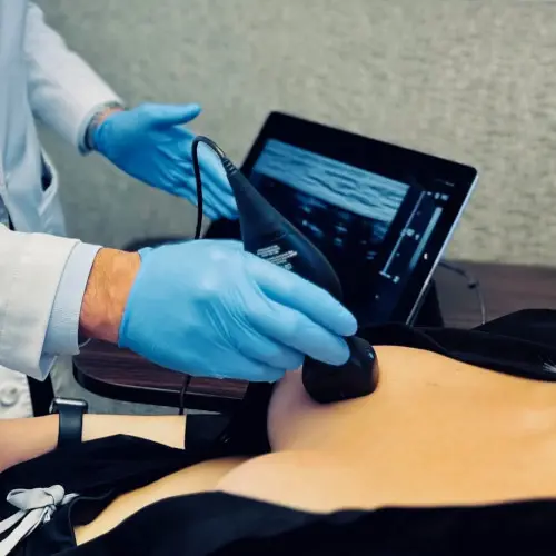 7-screening Medical professional in blue gloves performing a breast ultrasound